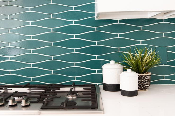 Teal kitchen tiles as a backsplash with black and silver kitchen utensils and features