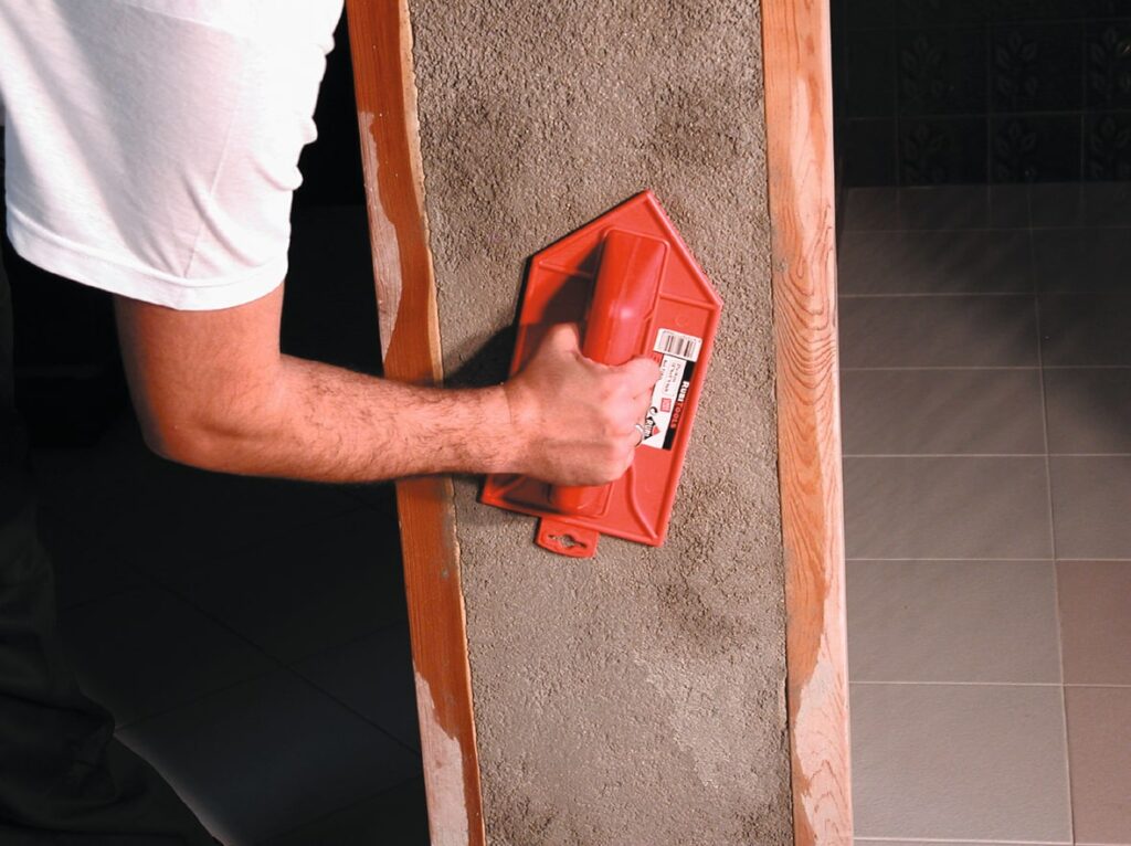 A professional using a groat float on a piece of wall.