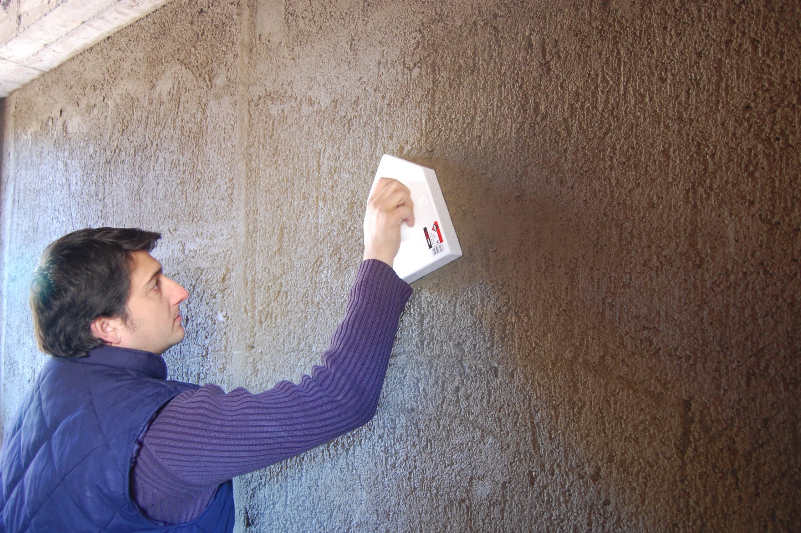 Professional using a plastic pointed grout float on the wall.