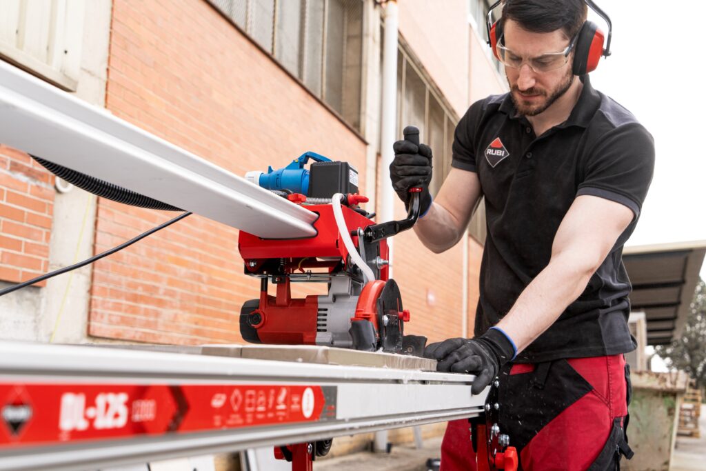 Professional using a wet saw to cut a tile.