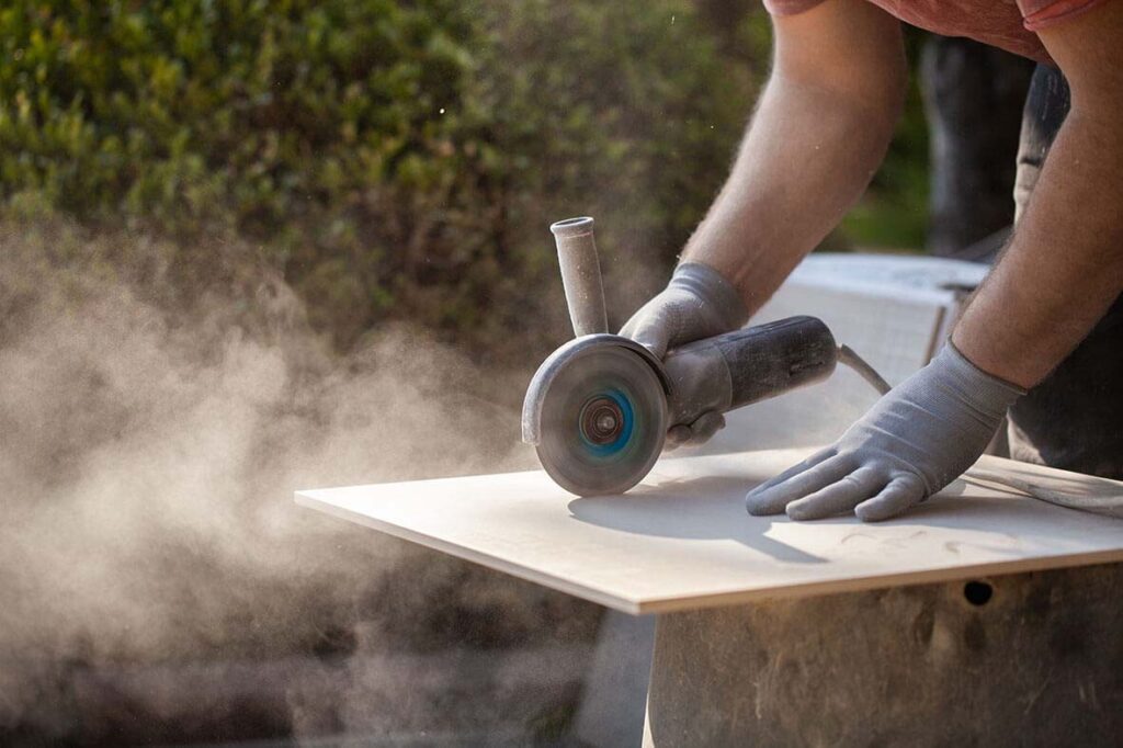 Tiler using a grinder to cut a shape in a tile.