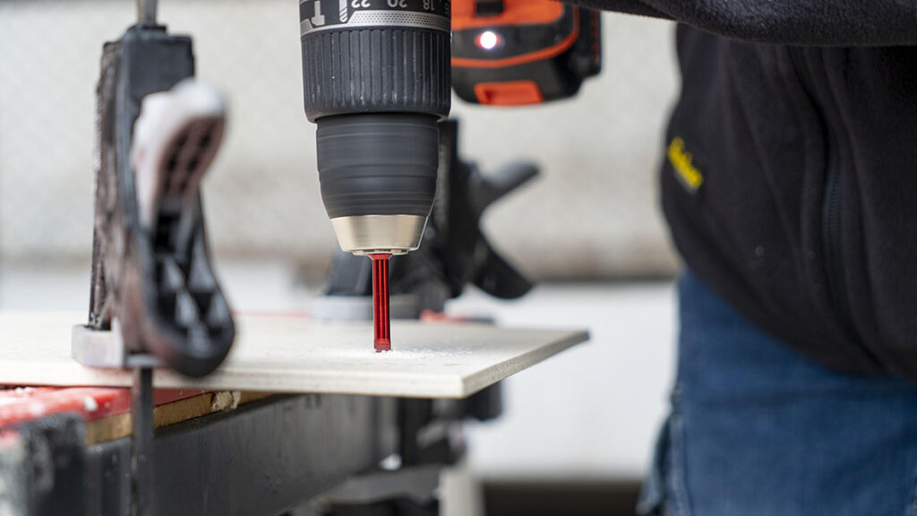 Tiler using a drillbit to cut a hole in a tile.