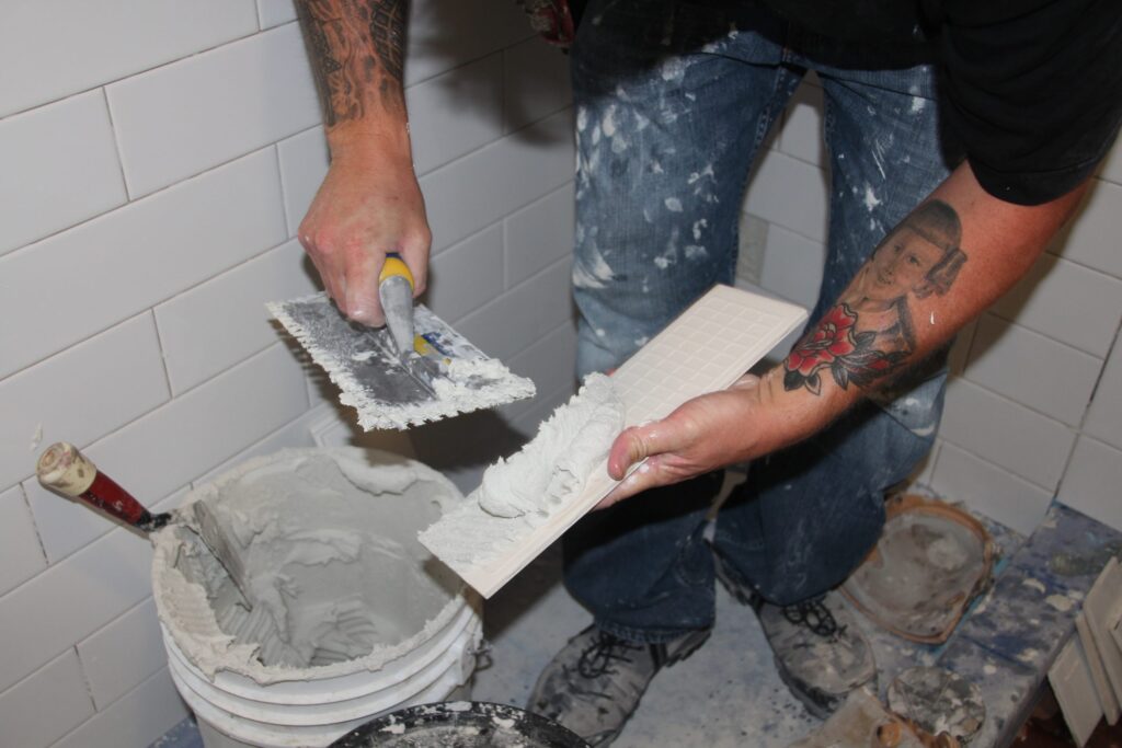 Close up of a tiler back buttering a narrow tile.