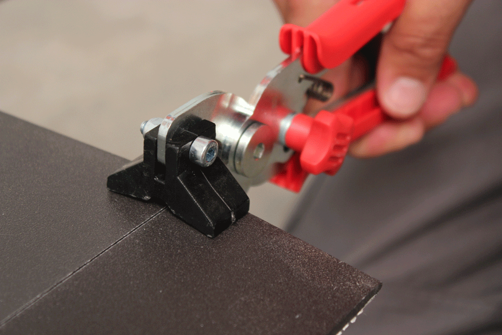 With the breaking pliers, pressure is applied to each side of the cut of the tile.