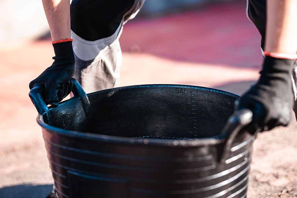 A worker holding a large rubber bucket