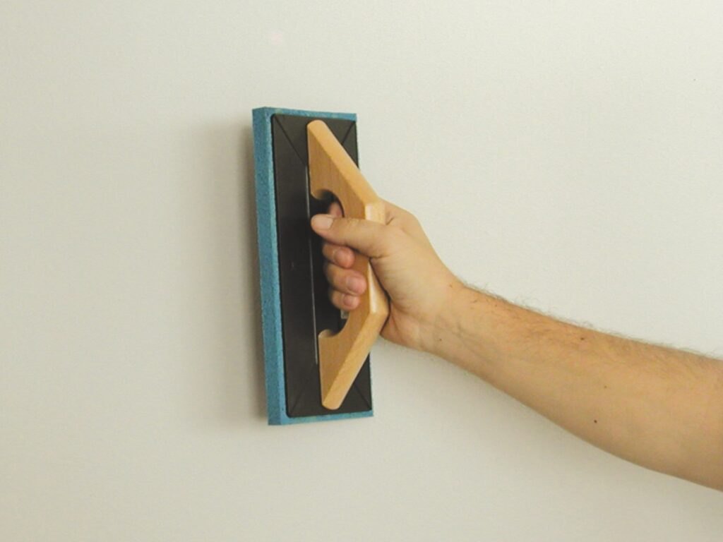 Primo piano di una spatola per stucco in uso su una parete.
