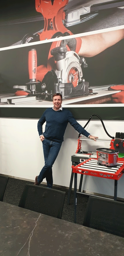 De directeur van RUBI Benelux poseert bij een zaagmachine.