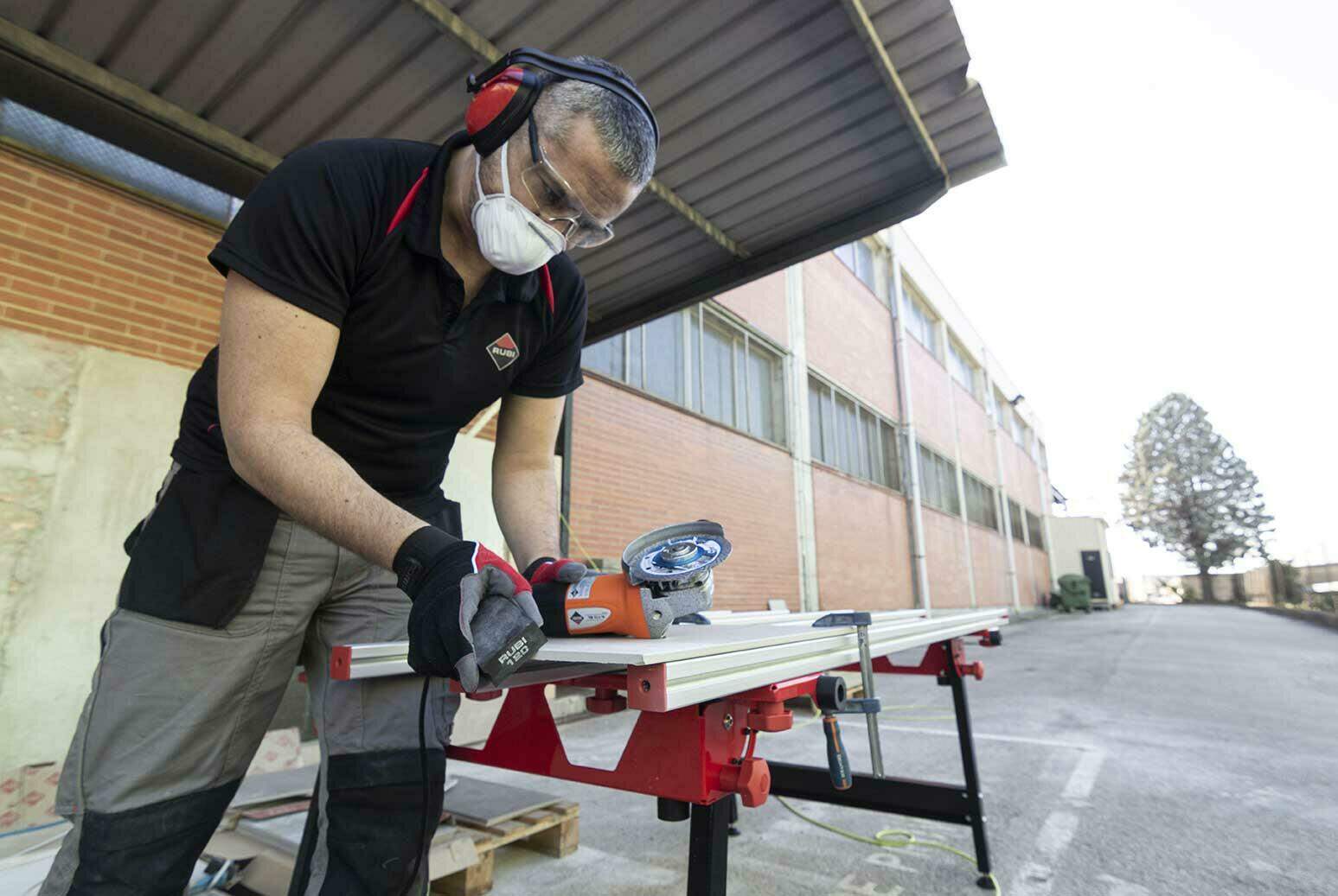 Een RUBI vakman scherpt met een polijstpad, na het zagen van een tegel met een diamantzaagblad, de scherpe kanten van de tegels af.