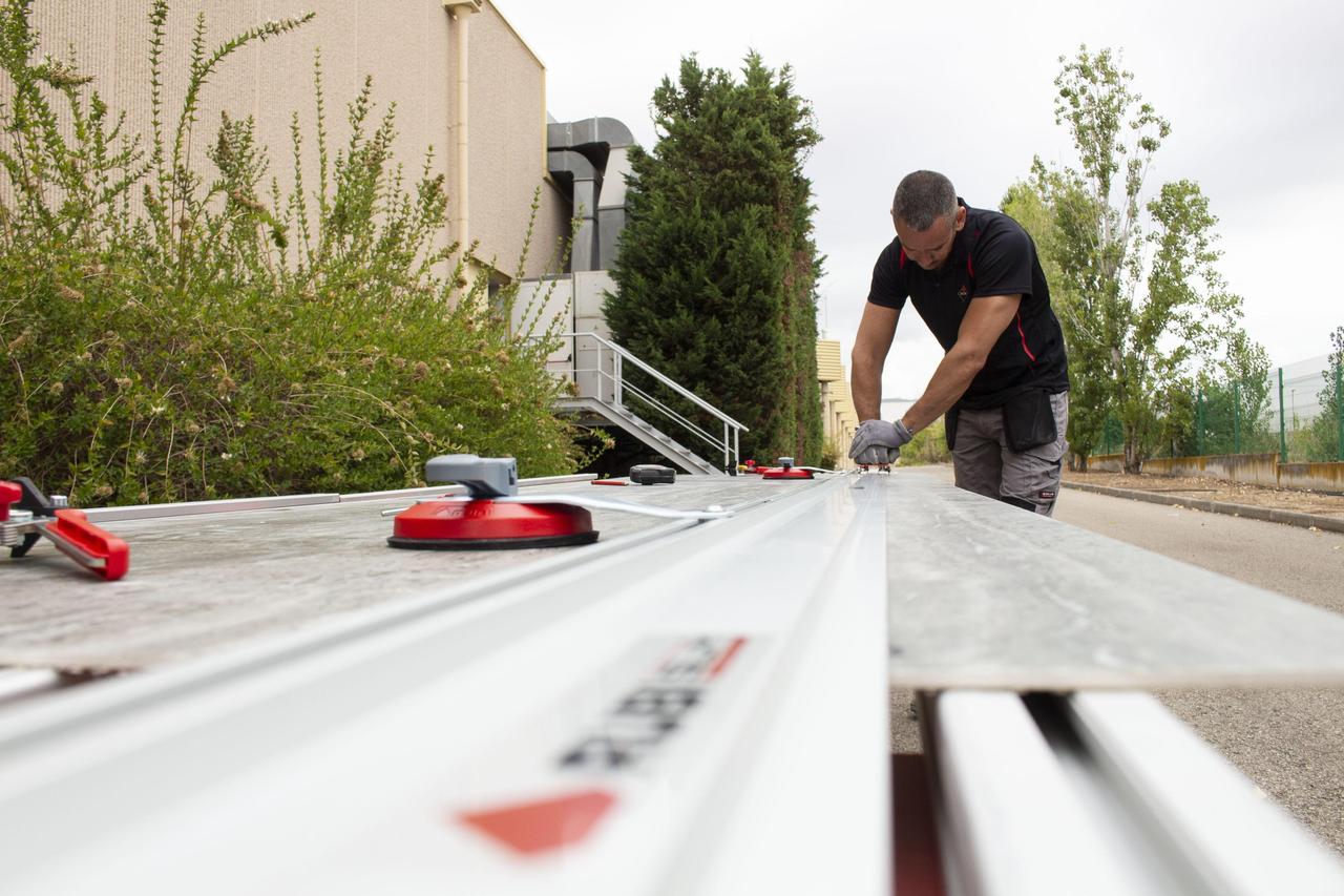 Een keramische plaat wordt in de buitenlucht op een grote werktafel gesneden met de SLIM CUTTER PLUS handsnijder van RUBI.