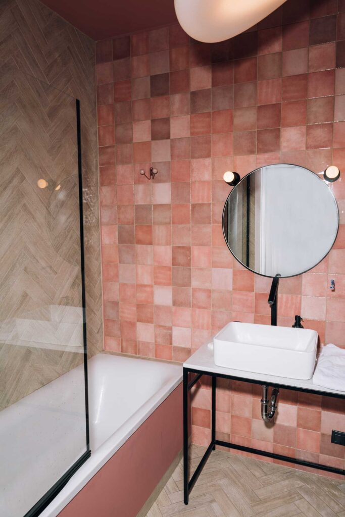  Gekleurde roze tegels in een badkamer, gecombineerd met houtlook. 