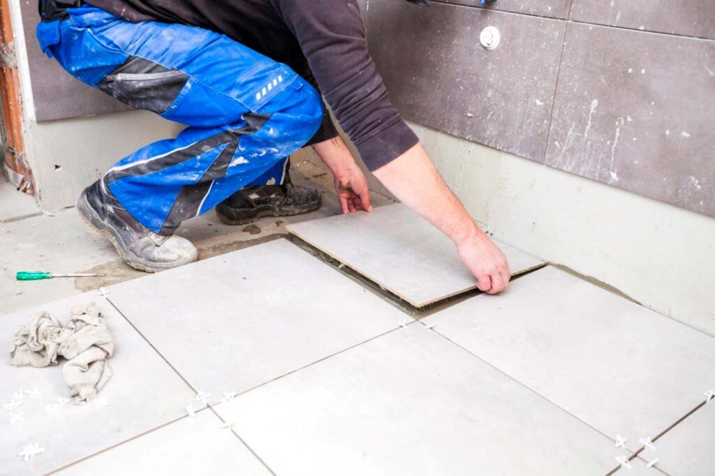 person laying tile in a bathroom